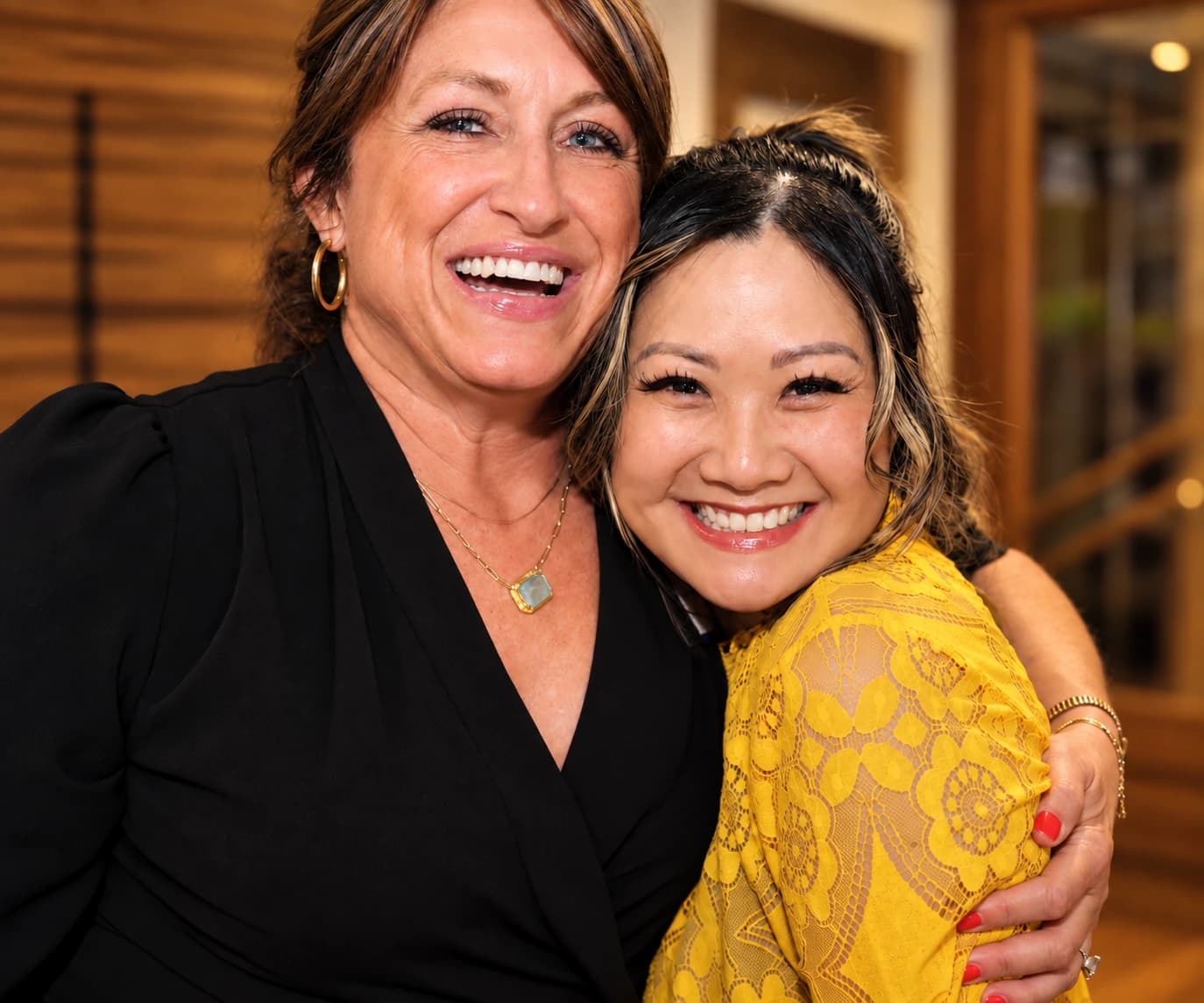 Two friends hugging and laughing at a Curated Connections singles evening