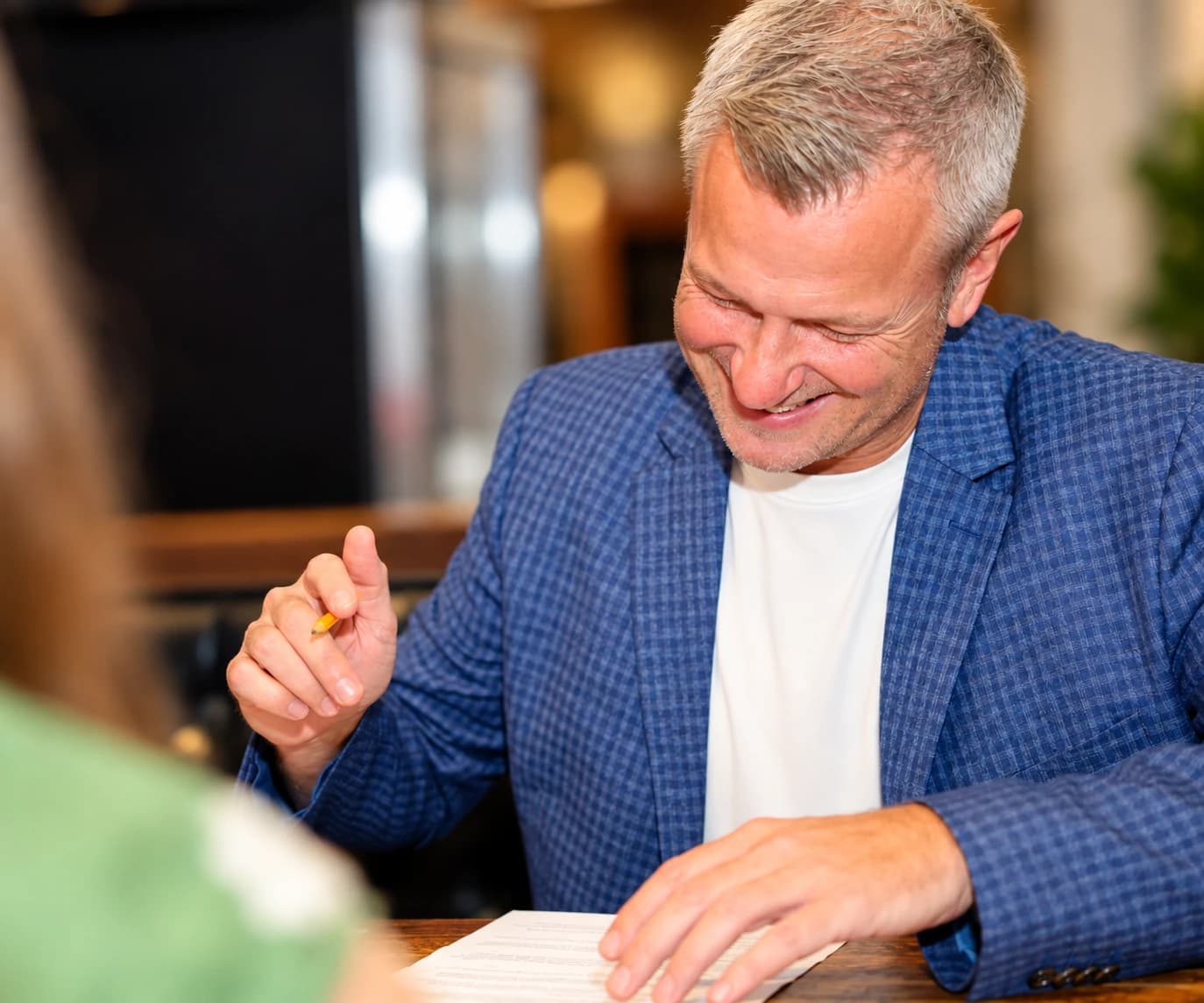 A guest in a blazer smiling as he marks his card between conversations